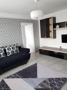 a living room with a black couch and a table at Ana Apartament in Râmnicu Vâlcea
