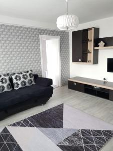 a living room with a black couch and a tv at Ana Apartament in Râmnicu Vâlcea