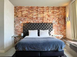 a bedroom with a brick wall and a bed at Van der Gang Suites uniek design in hartje Dokkum in Dokkum