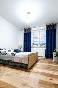 a bedroom with blue curtains and a bed with a wooden floor at Apartament Boryna in Łomża