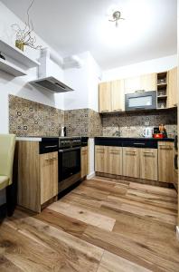 a kitchen with wooden cabinets and wooden floors at Apartament Boryna in Łomża