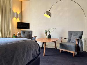 een slaapkamer met een bed en 2 stoelen en een tafel bij Van der Gang Suites in Dokkum