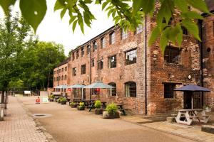 un edificio de ladrillo con mesas y sombrillas delante en YHA Ironbridge Coalport en Coalport