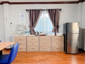 a kitchen with a refrigerator and a table and a window at 24 Hostel Donmuang in Thung Si Kan
