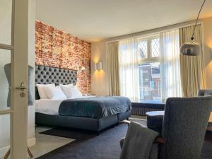 een hotelkamer met een bed en een bakstenen muur bij Van der Gang Suites in Dokkum