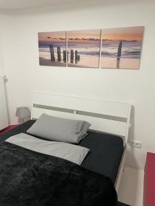 a bedroom with a bed with three paintings on the wall at Kastanienallee 7 in Hamburg