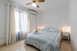 - une chambre blanche avec un lit et un ventilateur de plafond dans l'établissement Casa Alamos, à Nerja