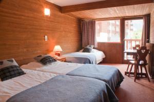 a room with two beds and a desk with a window at Les Crêtes Blanches in Val dʼIsère