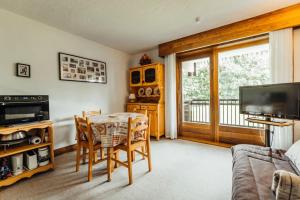 a living room with a table and chairs and a television at Studio with balcony and views of the golf course and surrounding mountains in Megève