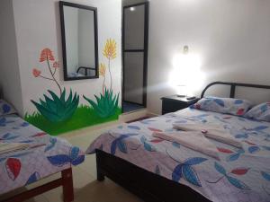 a bedroom with two beds and a painting on the wall at Casa Pacha in Guaduas