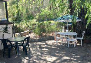 eine Terrasse mit Tischen, Stühlen und einem Sonnenschirm in der Unterkunft Kenata-Fairway in Perth