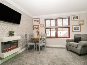 uma sala de estar com lareira e uma mesa e cadeiras em Andra Ghyll em Keswick