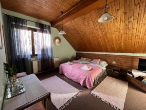 ein Schlafzimmer mit einem rosa Bett und einer Holzdecke in der Unterkunft Art Pension dans le Parc in Banská Bystrica