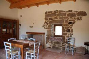 a room with a table and a stone fireplace at Stazzo Gallurese La Cugara in Aglientu