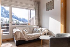 uma sala de estar com um sofá e uma grande janela em Comfortable studio with terrace and mountain views em Megève