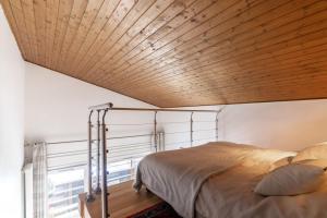 um quarto com uma cama e um tecto de madeira em Comfortable studio with terrace and mountain views em Megève