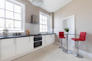 
a kitchen with white cabinets and white appliances at 2 Bedroom High Street Duplex Apartment in Cheltenham
