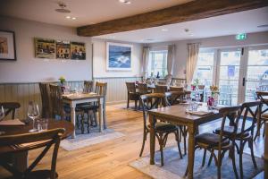 a restaurant with wooden tables and chairs and windows at The Red Lion at Hellidon in Daventry