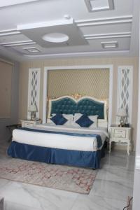 a bedroom with a large bed with a blue headboard at jawharat alshlal Establishment in Hafr Al Baten