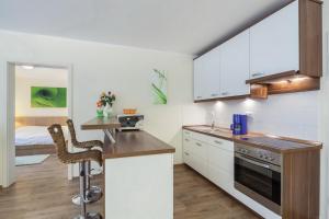 - une cuisine avec des placards blancs, une table et un lit dans l'établissement Residenz Seestern Wohnung 22, à Boltenhagen