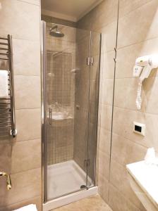 una doccia con porta in vetro in bagno di Corona D'Italia a Firenze