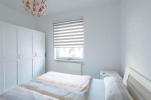 a white bedroom with a bed and a window at Zentral gelegene Wohnung in Hannover