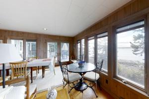 comedor con mesa, sillas y ventanas en Maddock Cove Cabin, en Southport