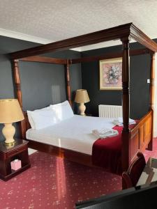 a bedroom with a canopy bed and two lamps at Caledonian Hotel in Dumfries +21 photos
