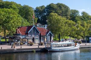 a boat docked in front of a building on a river at Villa Søholt - Silkeborg Bed and Breakfast in Silkeborg