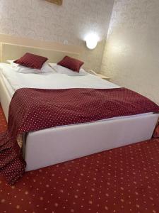 una camera da letto con un grande letto con lenzuola e cuscini rossi di Hotel Miraj - Restaurant & Sauna & Biliard a Poiana Brasov