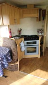 a small kitchen with a stove and a couch at Family Fun 2-Bed caravan family romney Marsh in Burmarsh