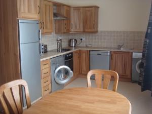 a kitchen with a table and a refrigerator and a dishwasher at Sun Apartments in Enniscrone