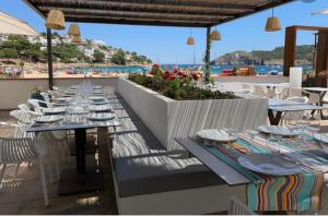 a row of tables on a patio with a view of the ocean at Résidence Cala Montgo in L'Escala