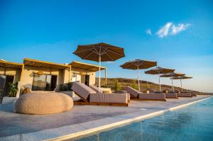 una fila de sillas y sombrillas junto a una piscina en Amaranto Evgatis Limnos, en Kondiás