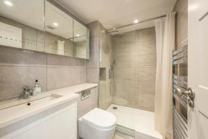 a white bathroom with a toilet and a shower at Cleveland Street by Q Apartments in London