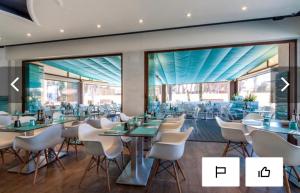 a restaurant with white chairs and tables and windows at Résidence Cala Montgo in L'Escala