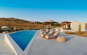a pool with chairs and umbrellas next to a house at Amaranto Evgatis Limnos in Kondiás