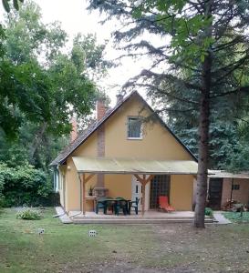Cette petite maison jaune dispose d'une terrasse et d'une table. dans l'établissement Borostyán Vendégház, à Tiszaug