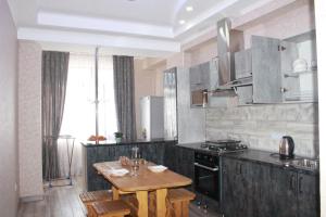 a kitchen with a wooden table and a stove at Отдельная квартира с видом на Ботанический садWiFi in Bishkek