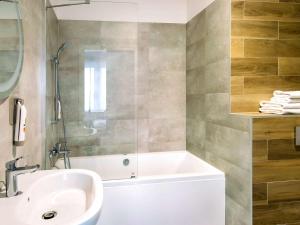 a bathroom with a white tub and a sink at ibis styles Grudziadz in Grudziądz