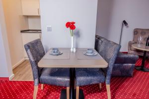 a table with two chairs and a vase with flowers at Hotel KonradP Holzkirchen in Holzkirchen