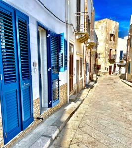 an alley with blue shutters on a building at Il Muretto in Marettimo