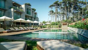 何塞伊格纳西奥Casagrande Hotel & Beach Club的建筑物旁边有带椅子和遮阳伞的游泳池