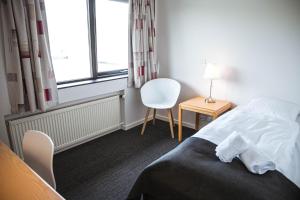 a bedroom with a bed and a chair and a window at Hotel Runavík in Runevig