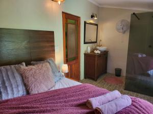 a bedroom with a bed with pink blankets and a sink at Rosenhof Garden Cottage in Clanwilliam +65 photos