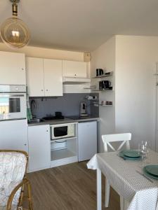 a kitchen with white cabinets and a table and a table and chairs at La Digue Vue mer 3 étoiles in Pléneuf-Val-André