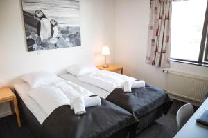 two beds in a hotel room with a penguin painting at Hotel Runavík in Runevig