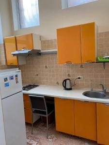 a kitchen with orange cabinets and a sink and a refrigerator at PANORAMI Apart Hostel in Lviv in Lviv