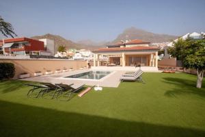 a yard with chairs and a swimming pool and a house at 5 bedrooms Villa Costa Adeje in Adeje