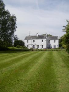 a large white house with a large grass field at The Naight House in Gloucester